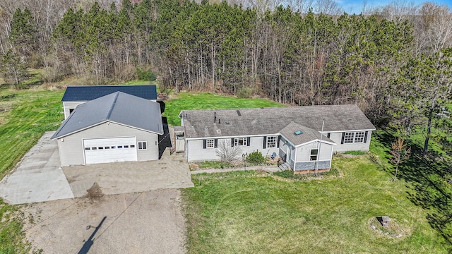 view of front of property featuring a view of trees, a front lawn, driveway, and a detached garage