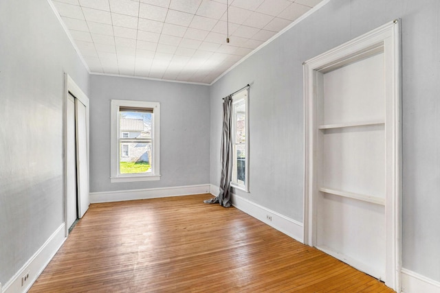 unfurnished room with crown molding, baseboards, and wood finished floors