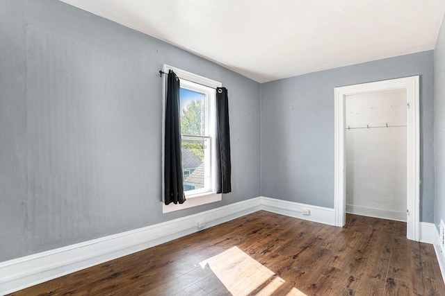 unfurnished bedroom with baseboards, a closet, and dark wood-style floors