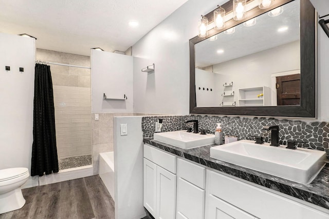 full bath with a sink, wood finished floors, and tiled shower