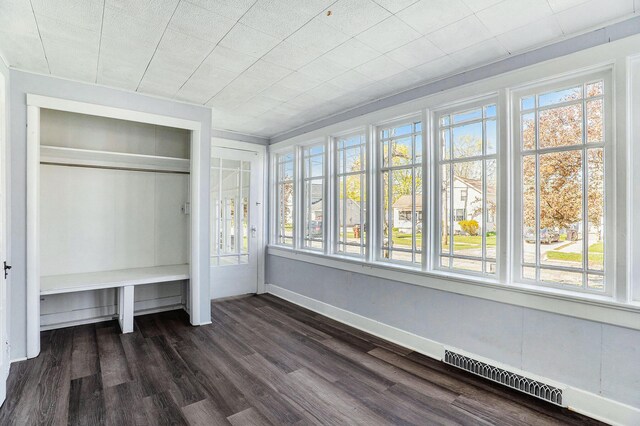 unfurnished bedroom with baseboards, multiple windows, dark wood finished floors, and visible vents