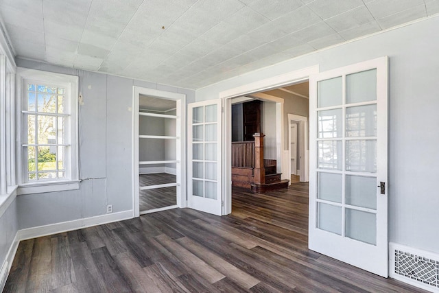 empty room with stairs, baseboards, visible vents, and dark wood-style floors