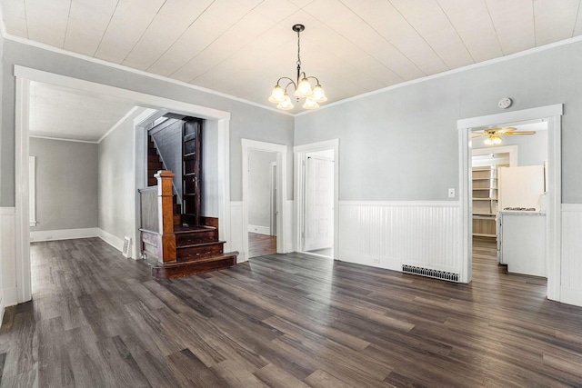 unfurnished dining area featuring a wainscoted wall, ornamental molding, dark wood finished floors, and stairs