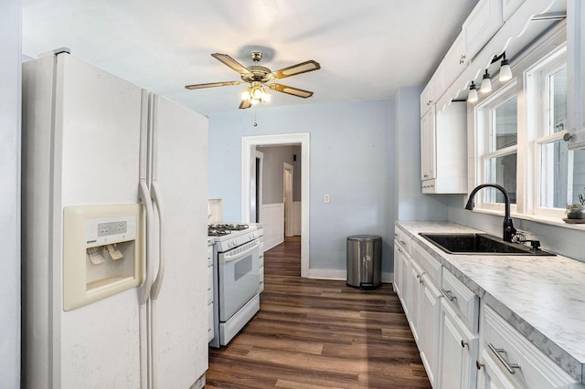 kitchen featuring dark wood finished floors, a sink, baseboards, white appliances, and white cabinetry