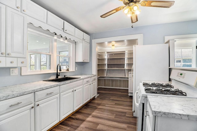 kitchen with a sink, dark wood-style floors, white gas range, and a healthy amount of sunlight