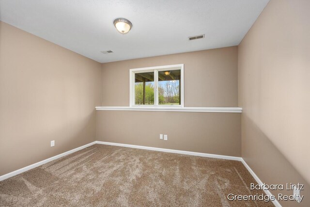 spare room with carpet floors, baseboards, and visible vents