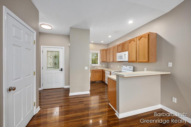 kitchen featuring white appliances, a peninsula, dark wood-style flooring, and light countertops
