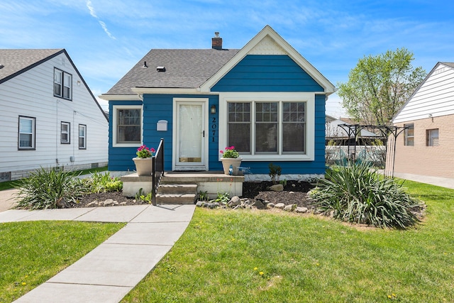 bungalow-style home with a shingled roof, a chimney, and a front yard