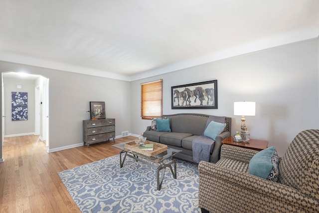 living room featuring baseboards, light wood finished floors, and visible vents