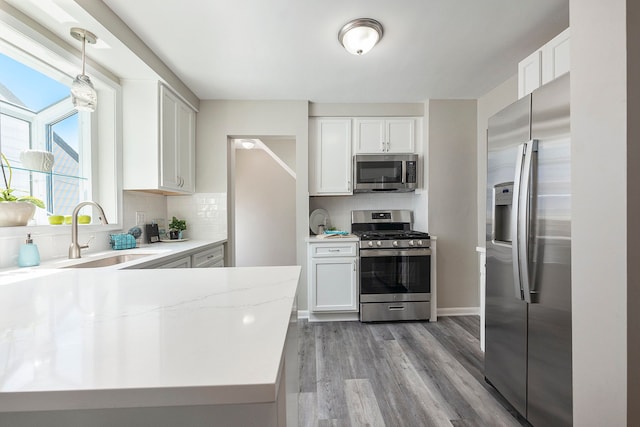 kitchen featuring backsplash, white cabinetry, appliances with stainless steel finishes, and light wood-style floors