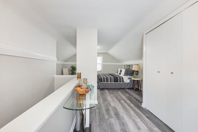 bedroom featuring baseboards, a closet, light wood-style flooring, and lofted ceiling
