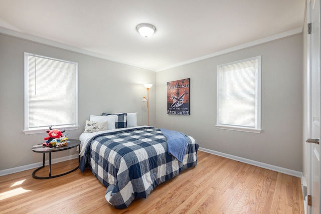 bedroom featuring baseboards, ornamental molding, and light wood-style floors
