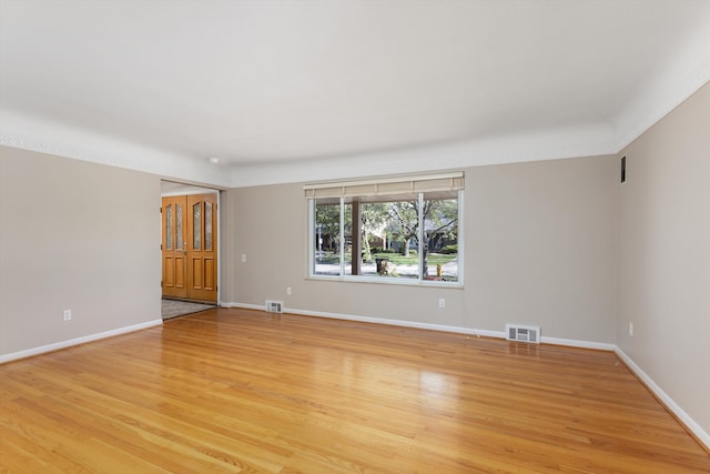 spare room featuring visible vents, light wood finished floors, and baseboards