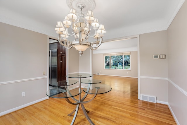 unfurnished dining area with a notable chandelier, visible vents, baseboards, and light wood-style floors