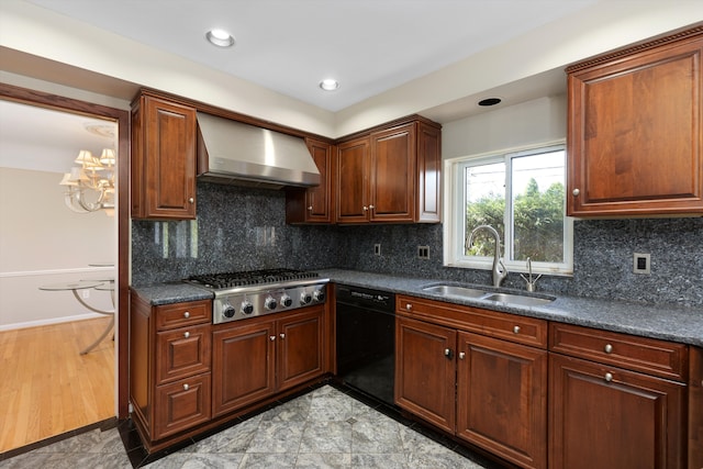 kitchen with wall chimney range hood, dark countertops, a sink, dishwasher, and stainless steel gas cooktop