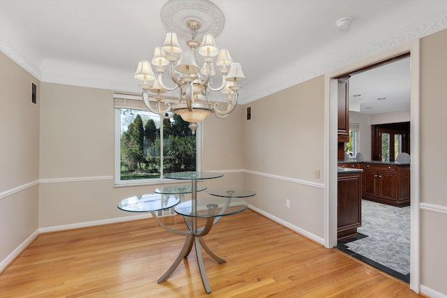 unfurnished dining area with baseboards, an inviting chandelier, light wood-style flooring, and visible vents