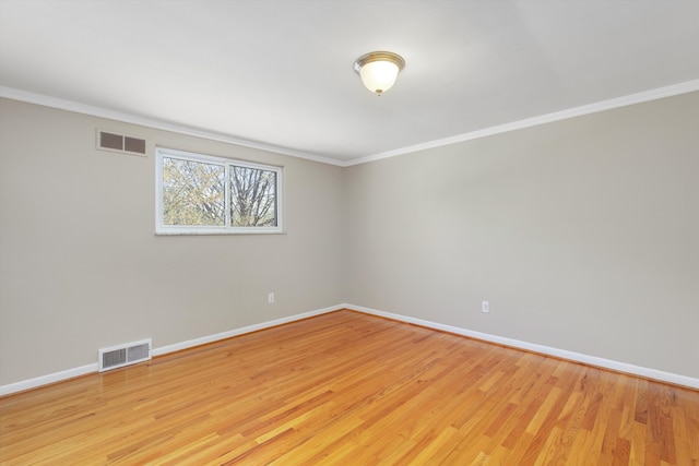 empty room with baseboards, ornamental molding, light wood finished floors, and visible vents