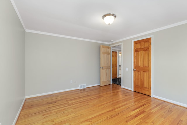 spare room with visible vents, ornamental molding, baseboards, and light wood-type flooring
