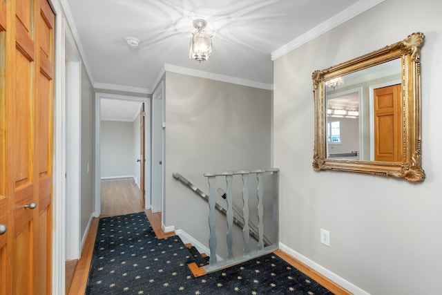 hallway featuring baseboards, ornamental molding, and an upstairs landing