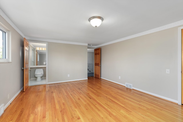 unfurnished bedroom featuring visible vents, ornamental molding, light wood finished floors, and baseboards