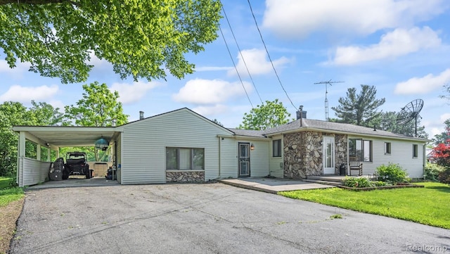 5304 E Frances Rd, Mount Morris, MI 48458 - view of front of home with stone siding, asphalt driveway, an attached carport, a chimney, and a front lawn