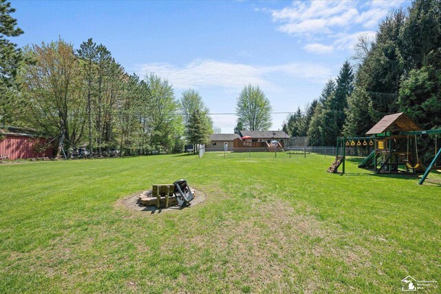 view of yard featuring fence, a playground, and a fire pit