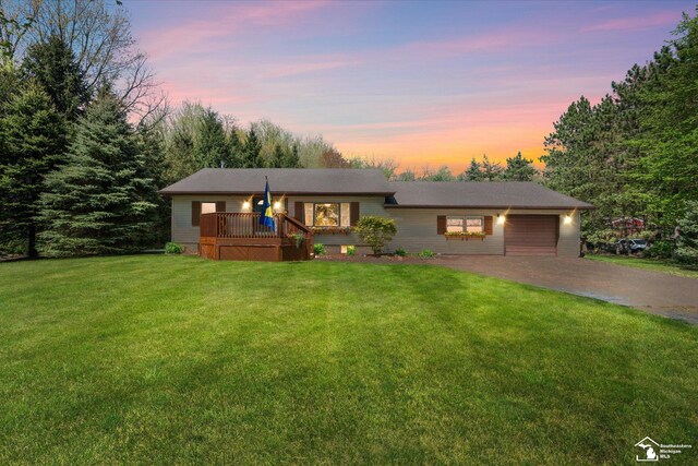 view of front facade featuring a yard, a deck, driveway, and a garage