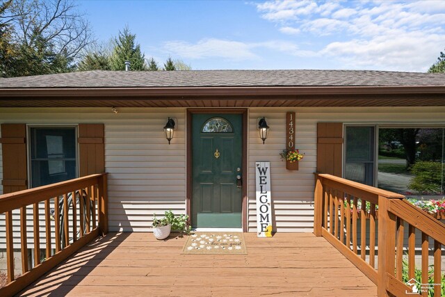 doorway to property with covered porch and roof with shingles