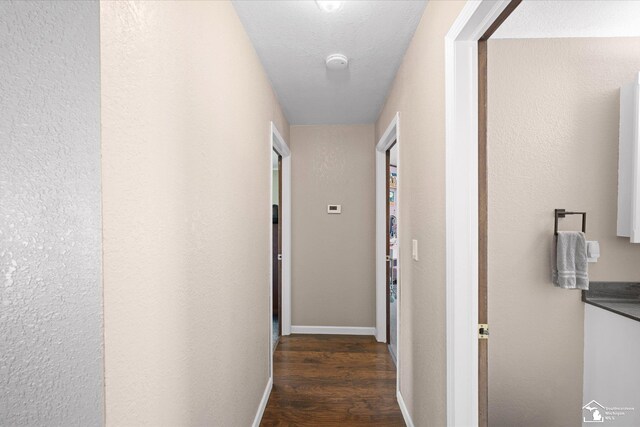 hall featuring baseboards and dark wood-type flooring