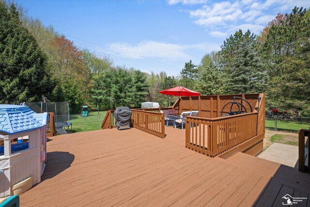 wooden deck with fence, a lawn, and a playground