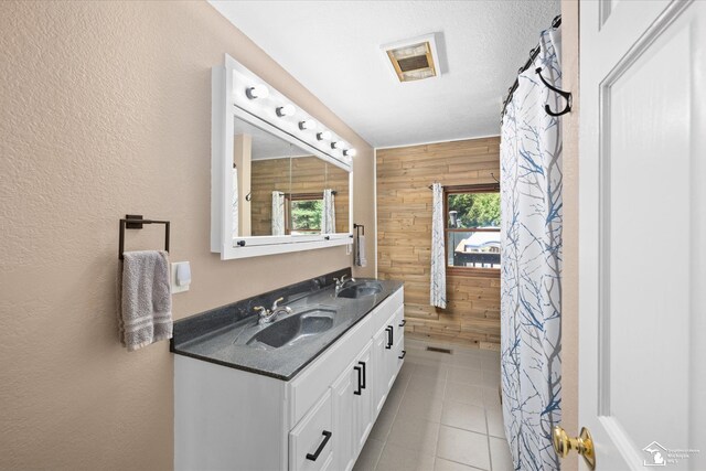 bathroom featuring a sink, a textured wall, wooden walls, and double vanity