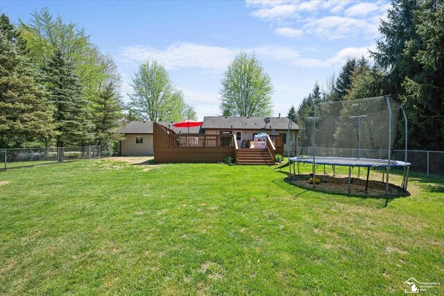 view of yard with a fenced backyard, a trampoline, and a wooden deck