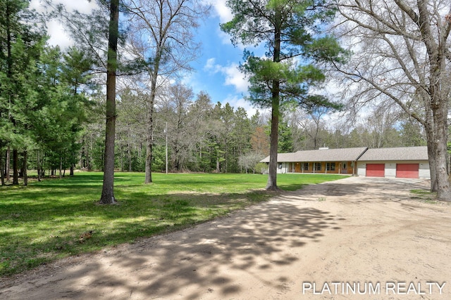 4334 Brunswick Rd, Holton, MI 49425 - view of front of home featuring dirt driveway, an attached garage, and a front lawn