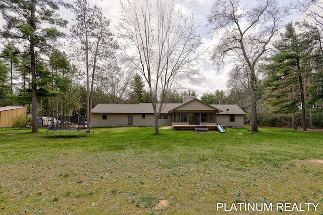 4334 Brunswick Rd, Holton, MI 49425 - back of house featuring a trampoline, a sunroom, and a lawn