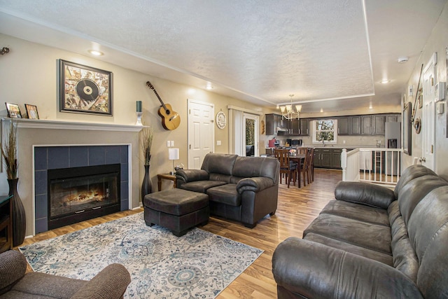 24260 Beacon Hill Ter, Mattawan, MI 49071 - living area featuring a textured ceiling, wood finished floors, a notable chandelier, and a tile fireplace