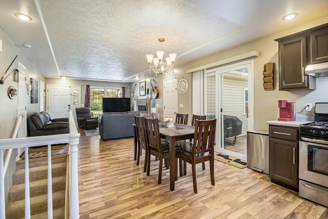 dining space with recessed lighting, light wood finished floors, a textured ceiling, and a chandelier