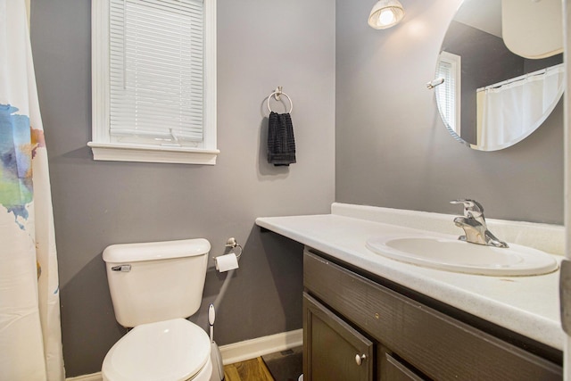 bathroom with baseboards, vanity, and toilet