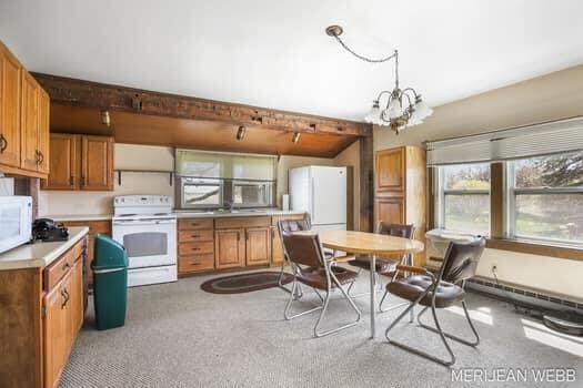 kitchen featuring brown cabinets, light countertops, a chandelier, light carpet, and white appliances