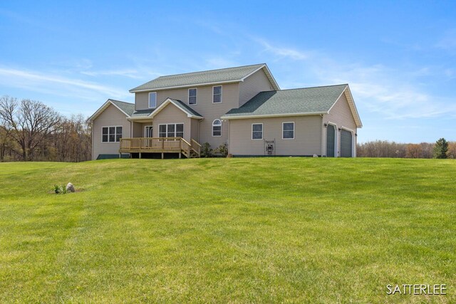 rear view of property with a lawn, a garage, and a deck