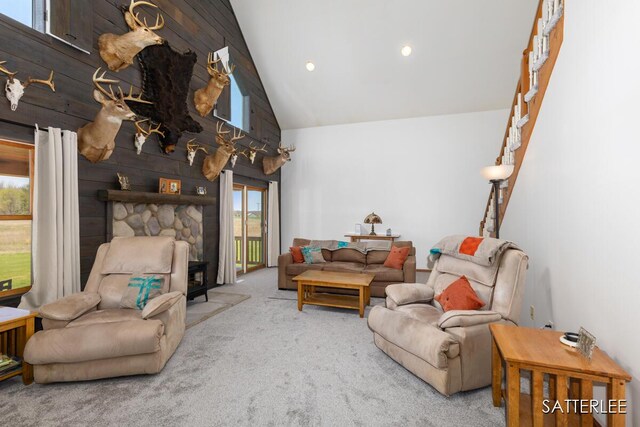 carpeted living area featuring high vaulted ceiling and wood walls