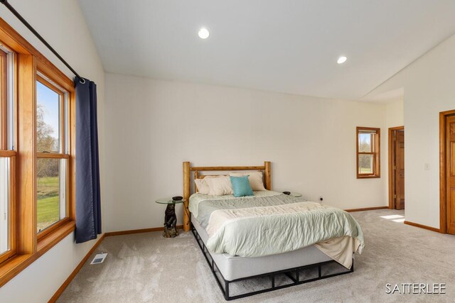 carpeted bedroom featuring baseboards, vaulted ceiling, and visible vents