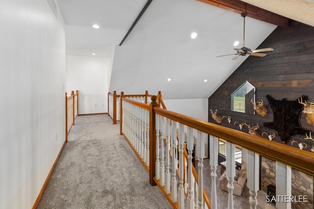 hallway featuring lofted ceiling with beams, wood walls, recessed lighting, baseboards, and an upstairs landing
