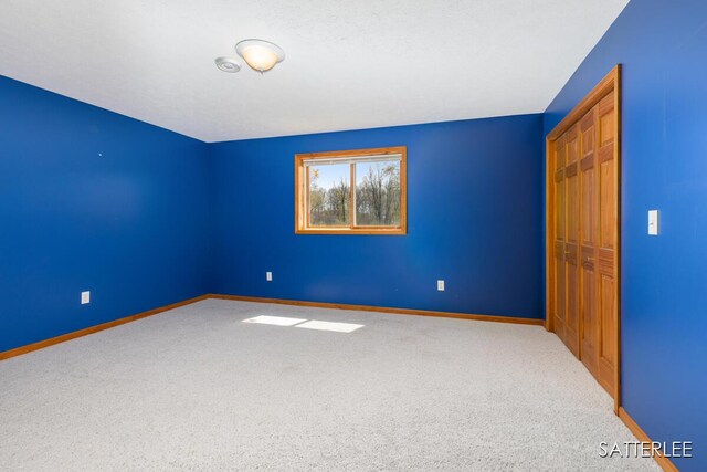 carpeted spare room featuring baseboards