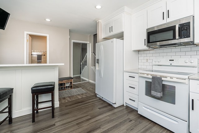 kitchen featuring dark wood-type flooring, recessed lighting, and white appliances