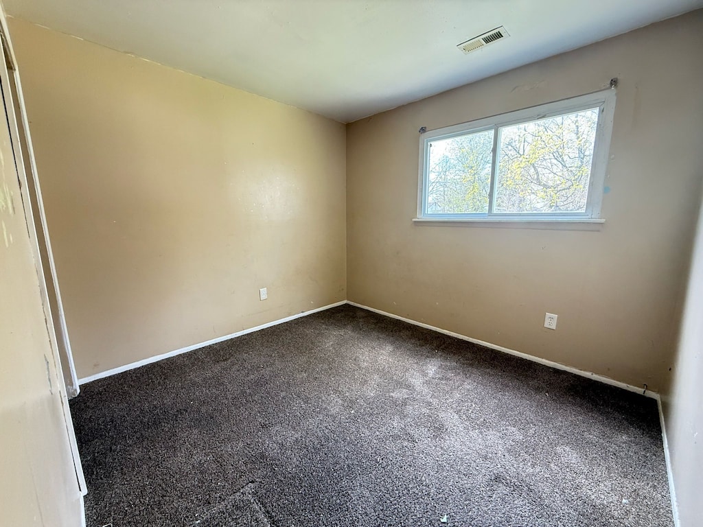 spare room with dark carpet and baseboards