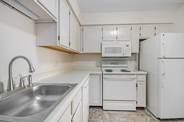 kitchen with white appliances, light countertops, white cabinetry, a sink, and stone finish flooring