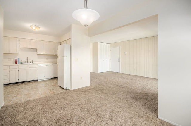 kitchen with pendant lighting, white appliances, light colored carpet, light countertops, and a sink