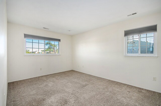 unfurnished room featuring baseboards, visible vents, and carpet