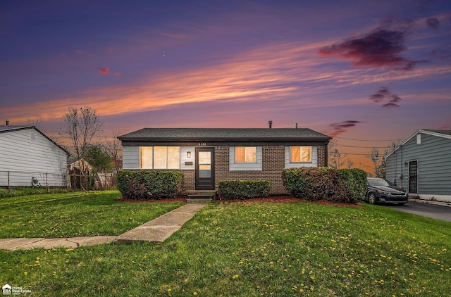 bungalow-style home with brick siding, fence, and a yard