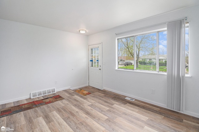 foyer entrance featuring baseboards, wood finished floors, and visible vents